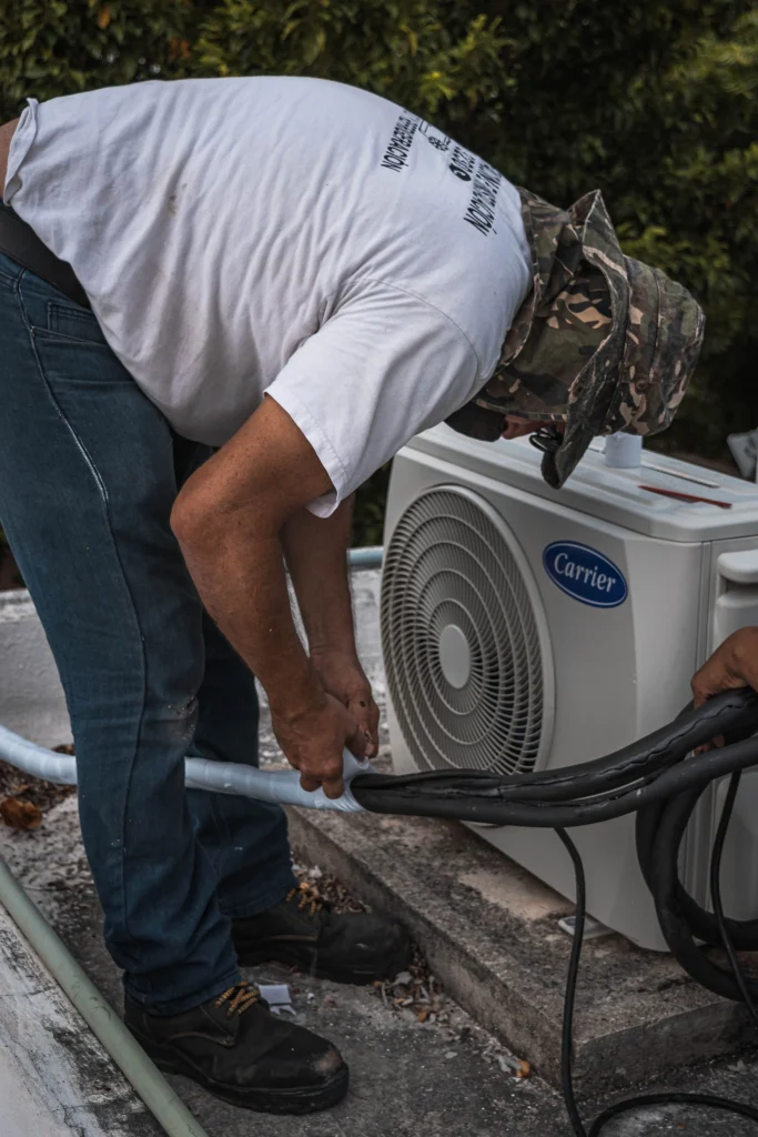 Air Conditioner Maintenance: Technician checking condenser coils and electrical components on a residential air conditioning system in Cape Coral, Florida.